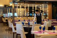 ein Kellner deckt Tische in einem Restaurant in der Unterkunft Paya Bunga Hotel Terengganu in Kuala Terengganu