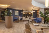 un ristorante con divano blu e tavoli e sedie di ibis London Earls Court a Londra