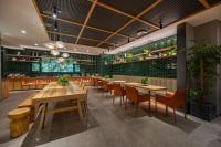 Un restaurante con mesas y sillas de madera y plantas. en Qiuguo Hotel Chongqing Guanyin Bridge Branch, en Chongqing