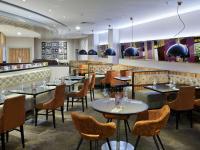 a restaurant with tables and chairs and a bar at Novotel London West in London