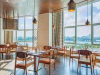 a restaurant with tables and chairs and large windows at Hilton Cairo Nile Maadi in Cairo