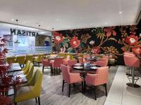 a restaurant with tables and chairs and a floral wall at Novotel London West in London