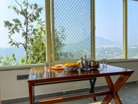 a table with a bowl of fruit on it in front of a window at Manika Homestay in Bhīm Tāl