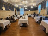 Un comedor con mesas y sillas blancas y candelabros. en Eides Hotel, en Høyanger