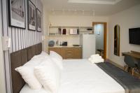a bedroom with a bed with white pillows and a refrigerator at Flat Casa Mauá in Rio de Janeiro
