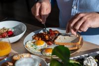 a person eating breakfast food on a table at Hotel Convictus Cracovia for business & travellers in Kraków
