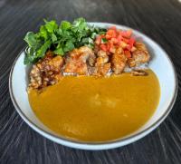 Un tazón de sopa con carne y verduras en una mesa. en New Little Ripper Boutique Hotel, en Tanah Lot