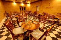 ein Restaurant mit Holztischen und -stühlen auf einem karierten Boden in der Unterkunft Desert Popular Resort & Camp in Jaisalmer