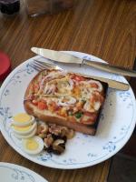 a slice of pizza on a plate with eggs and mushrooms at Haliluya Homestay in Magong
