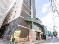 Un edificio alto con un cartel delante. en Tabist ASAHIKAWA STATION HOTEL, en Asahikawa