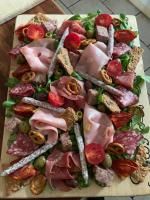 Chambre d'hôtes Sous Les Grands Chênes Cabane du CHENE في Saint-Étienne-de-Corcoué: كومة من اللحوم والخضراوات على لوح تقطيع