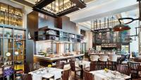 Un restaurante con mesas y sillas y un bar. en Siam Kempinski Hotel Bangkok, en Bangkok