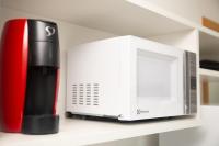 a red and black appliance sitting on a shelf next to a microwave at Flat Casa Mauá in Rio de Janeiro