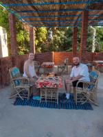 Dos personas sentadas en una mesa bajo una sombrilla. en Kashta Nubian Guest Houst, en Asuán