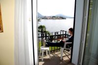 a woman sitting in a chair on a balcony looking at the water at Hotel Villa Ruscello in Baveno