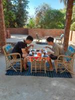 dos hombres sentados en una mesa comiendo comida en Kashta Nubian Guest Houst, en Asuán