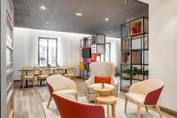 Una sala de espera con sillas, una mesa y estantes. en IntercityHotel Dortmund, en Dortmund