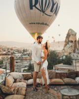 un hombre y una mujer parados frente a un globo de aire caliente en Kayatas Cave Suites, en Göreme