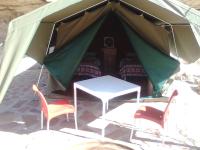 a tent with two chairs and a table and a bed at Hais Ra Tented Campsite in Khorixas