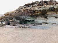 a building next to a rock wall with a tree at Hais Ra Tented Campsite in Khorixas