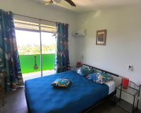 Un dormitorio con una cama con sábanas azules y una ventana. en Fare Arana Mooréa Guesthouse, en Atiha