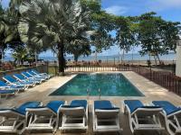 Una piscina con tumbonas y la playa. en Macaw Paradise, en Jacó