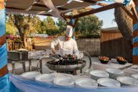 Simeri MareVOI Floriana Resort的厨师在烤架上用盘子准备食物。