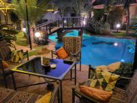 a resort with a pool and a table and chairs at Hacienda Ouaga in Ouagadougou