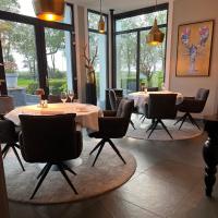 een eetkamer met tafels en stoelen en ramen bij Landhuis Logan Landing in Rilland