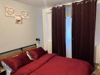 Un dormitorio con una cama con sábanas rojas y una ventana. en Hôtel Saint - Charles, en Rambouillet