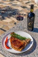 een witte plaat met een stuk vlees en een glas wijn bij La Casa Blanca in Vladimirescu