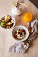 a table with two bowls of cereal and fruit and a glass of orange juice at Mileo in Kalo Livadi
