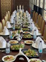 a long table with plates of food and bottles of water at Khabti Grand Hotel in Qal'at Bishah