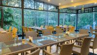 a restaurant with tables and chairs and large windows at Mainland Resorts & Spa by Kolaahalam in Yercaud