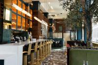 Un restaurante con un bar con sillas y árboles. en voco Hotel Napoleon Memphis by IHG, en Memphis