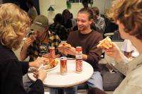 a group of people sitting around a table eating pizza at Gspot Hostels & Love Triangles Pizzeria in Lisbon