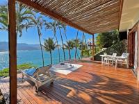 a wooden deck with a table and chairs and the ocean at Barra do Piuva Porto Hotel in Ilhabela