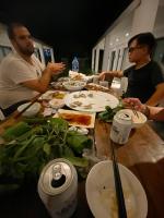 un grupo de personas sentadas a una mesa con comida en Coto Island Beach Village Homestay, en Dao Co To