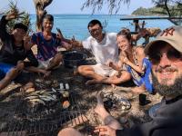 un grupo de personas sentadas alrededor de una parrilla en Coto Island Beach Village Homestay, en Dao Co To