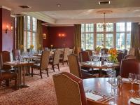 リミントンにあるElmers Court Hotelのテーブルと椅子と窓のあるダイニングルーム