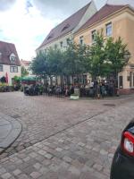 un groupe de personnes assises à des tables à l'extérieur d'un bâtiment dans l'établissement Ferienwohnung Rosso Vino 1, à Meissen