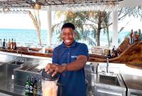 Zanziblue Waves Beach Resort في كيوينجوا: رجل واقف في مطبخ مع ابريق