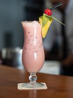 Un vaso de bebida rosa con una cereza encima. en Aparthotel Solifemar, en Castelldefels