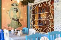 Una mesa con sillas azules y una foto de una mujer. en Hotel Chalet des Roses, en Antananarivo