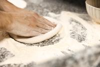 una persona amasando una masa en una mesa en Hotel Al Bivio - Pizzeria, Pool & Sauna, en Imer