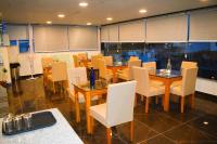 een restaurant met houten tafels en witte stoelen en ramen bij Hotel Shreya Galaxy with Swimming Pool- Best Property in Haridwar in Haridwār