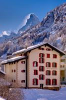 un hotel en las montañas con nieve en el suelo en Hotel Bahnhof, en Zermatt