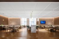 a dining room with tables and chairs and a tv at Atour Hotel Chongqing Jiangbei Airport Huanshan Park in Chongqing
