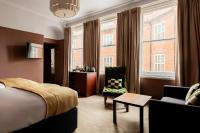 a hotel room with a bed and a chair and windows at The Brewers Inn in London
