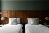 two beds in a room with wood paneling at The Brewers Inn in London